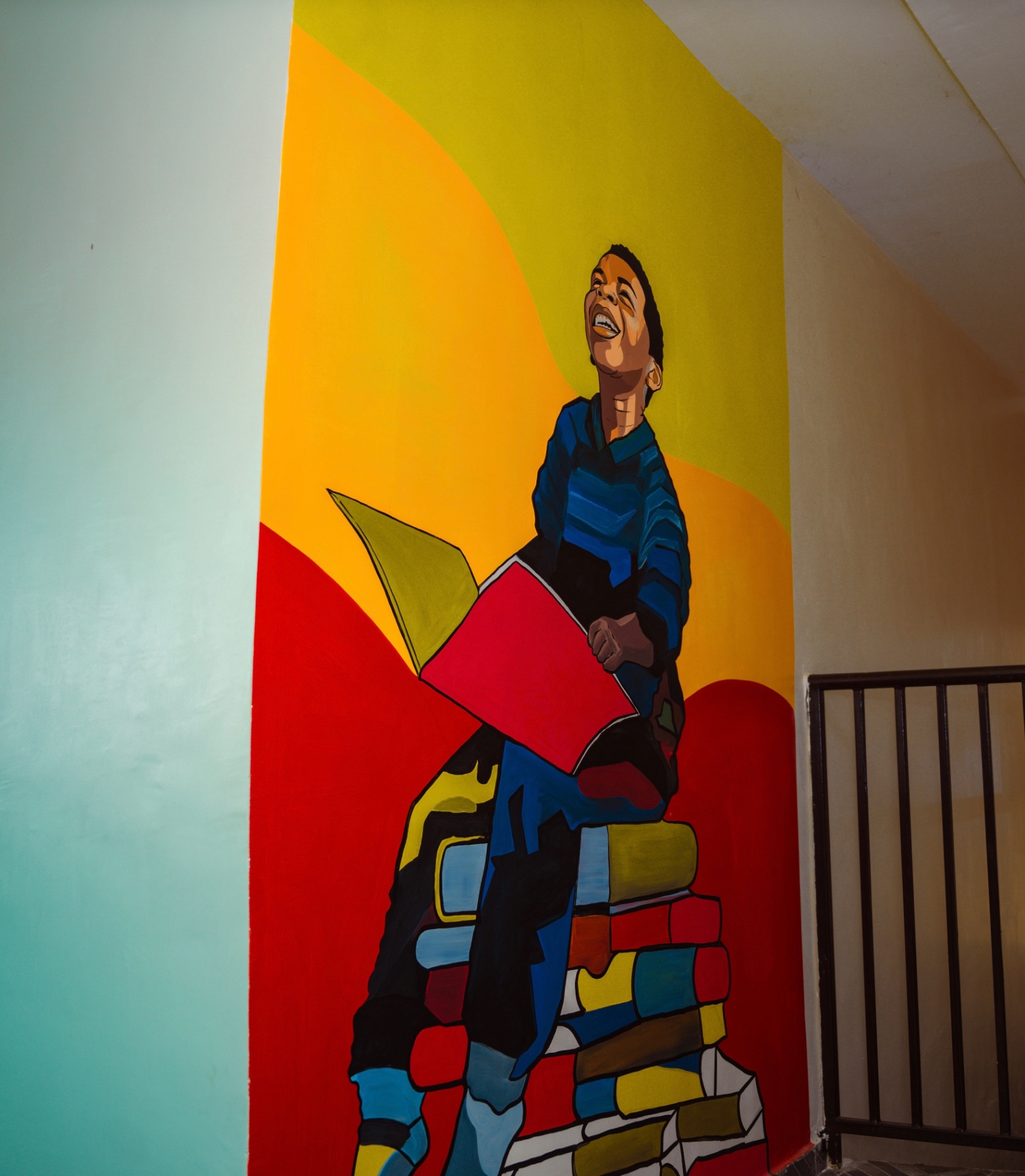 Hand-painted mural of a child reading on stacked books